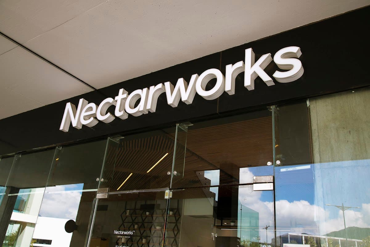 Fachada de vidrio de Nectarworks Carretera Nacional OMNIA con clientes tomando smoothies, vista exterior del local en Plaza Omnia