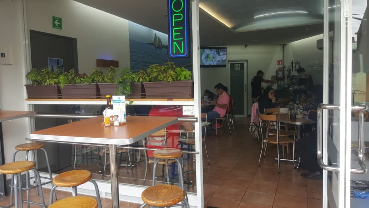 Mariscos Cocos Locos con su barra llena de camarones al ajillo y una mesa con botellas de cerveza artesanal, captura el ambiente nocturno