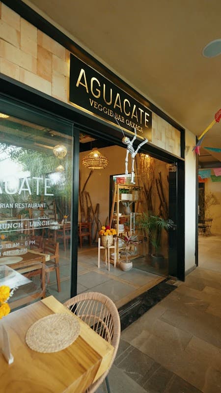Fachada de Aguacate Oaxaca en Reforma 703, con su letrero verde y la ventana llena de plantas, capturando la atmósfera matutina