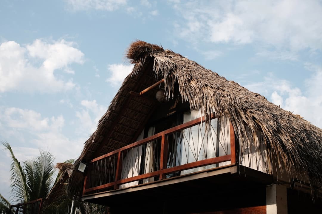Thatched roof bungalow with balcony against sky