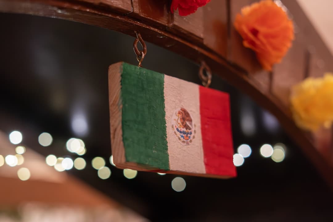 A small wooden mexican flag hangs with bokeh lights.