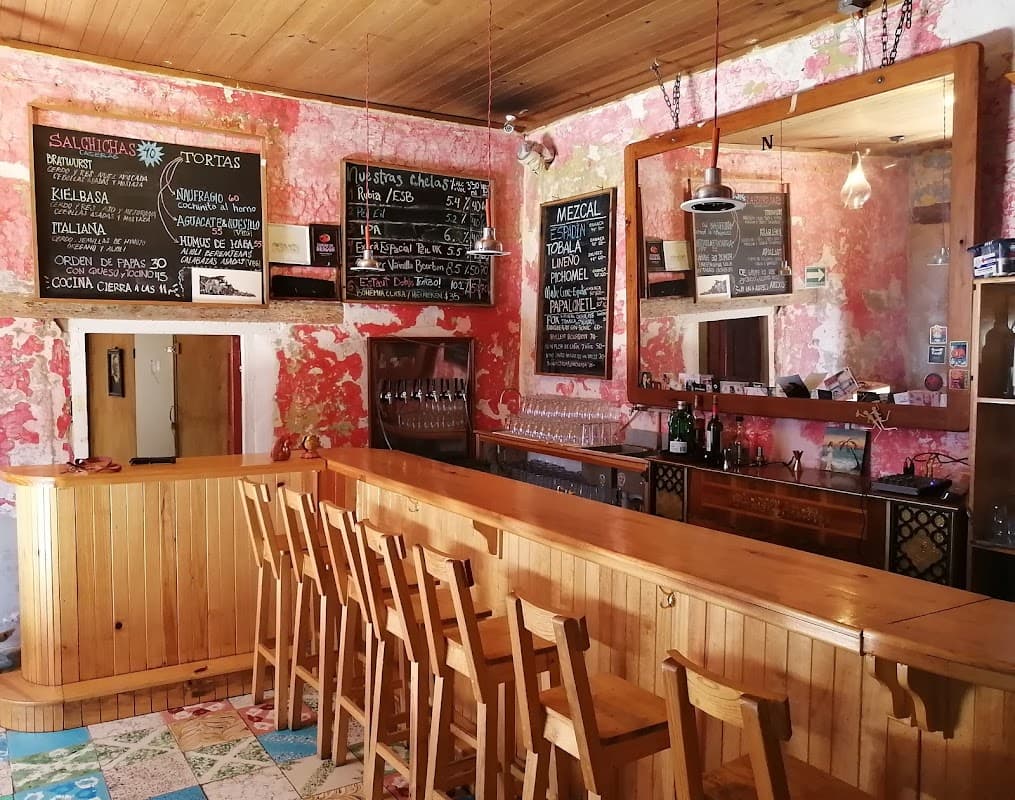 Exterior de Cervecería Naufragio con su jardín y mesas al aire libre, mostrando la barra de cervezas y el ambiente nocturno.