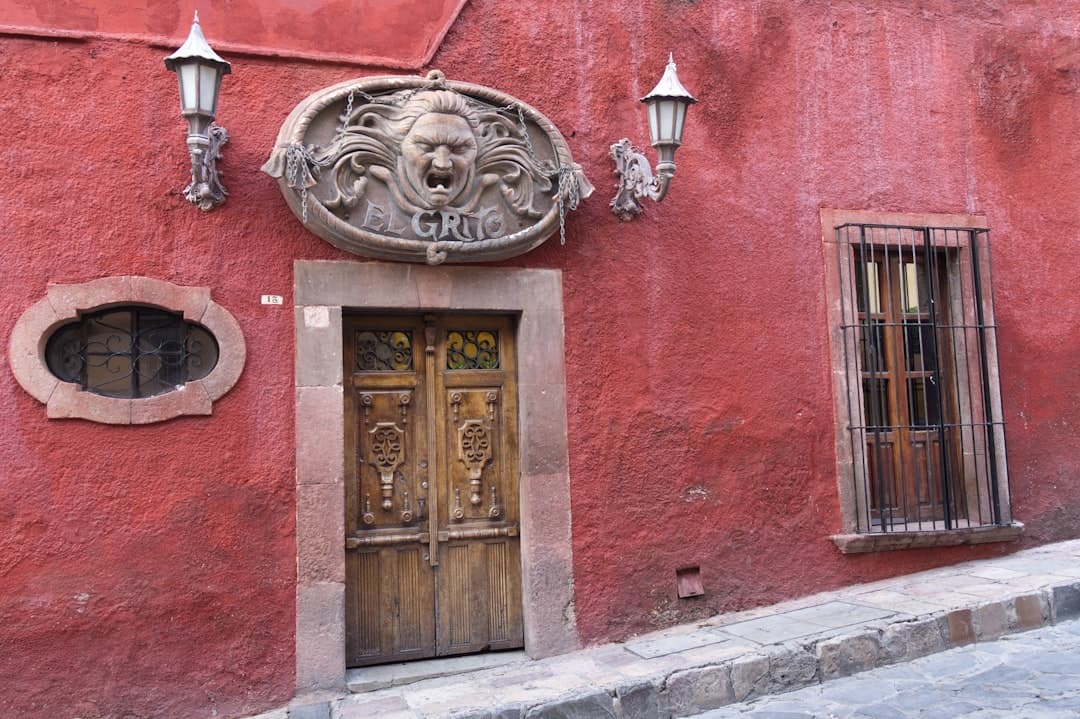A wooden door with carvings on a red wall.