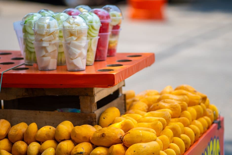 Vibrant display of fresh mangoes and fruit cups on a street stall in Mexico City.