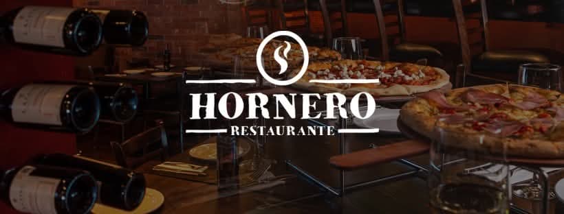 Vista del interior de Restaurante Hornero con horno de leña encendido y pizza recién salida, enfoque en la corteza crujiente