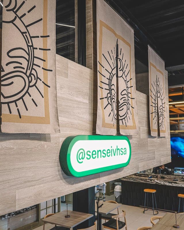 Interior de Sensei Sushi Bar con barra de sushi y platos coloridos