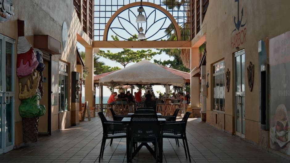 Scenic outdoor café with a tented dining area and sea view, surrounded by decorative elements.