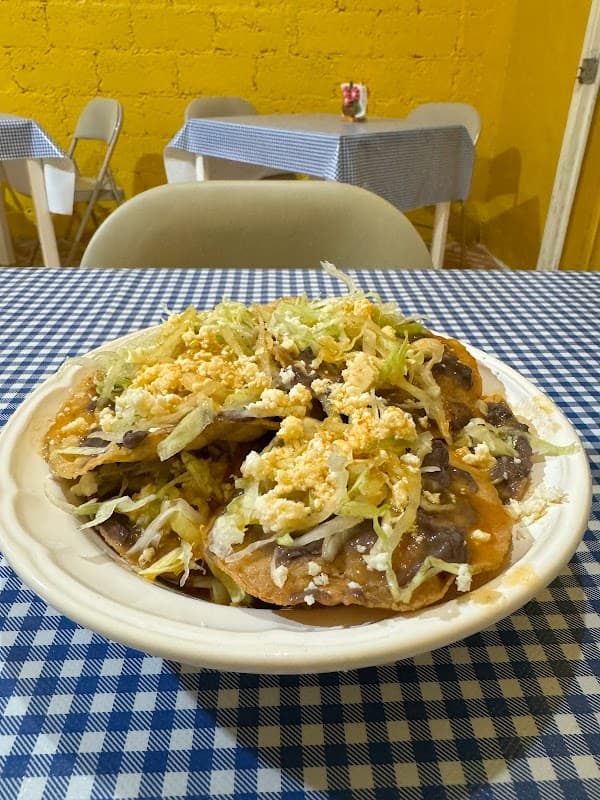 Carnitas "El Higuero" showing the grill with sizzling pork and a plate of three tacos on a wooden board