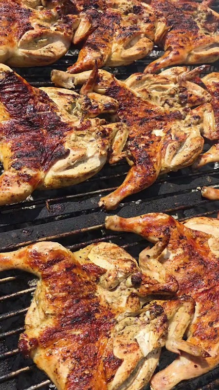 Pollo Mestizo en su fachada de Calle 21, con el mostrador de pollo a la parrilla y clientes en mesas al aire libre