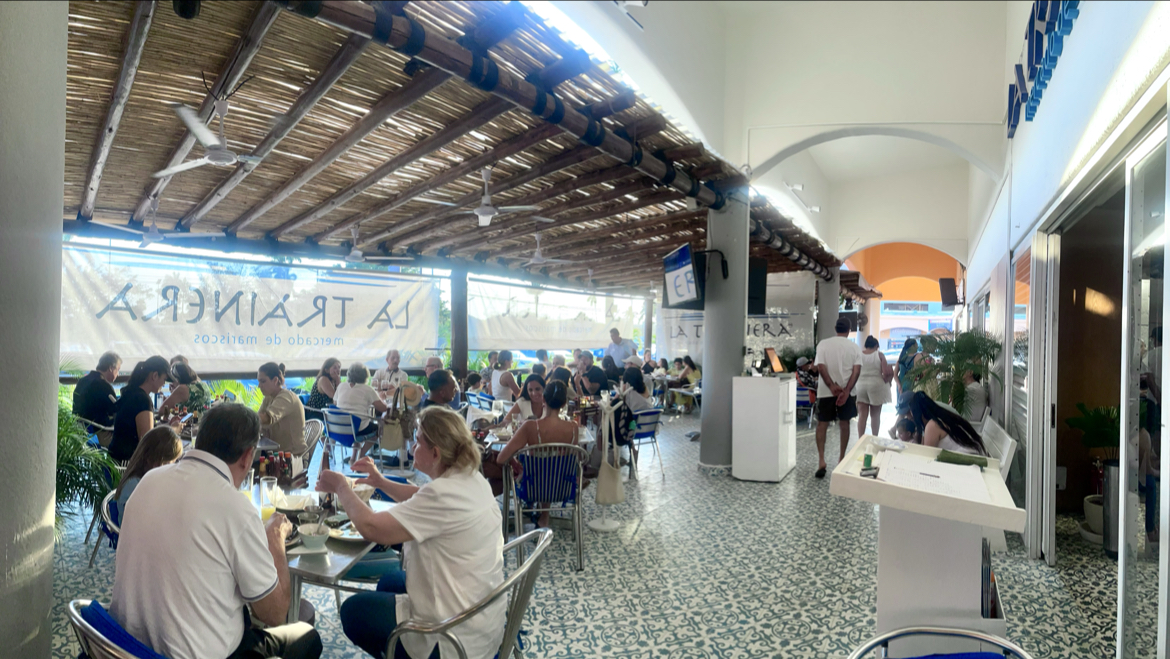 Exterior de Restaurant La Fogata con luces de neón, terraza llena de gente y platos de tacos al pastor