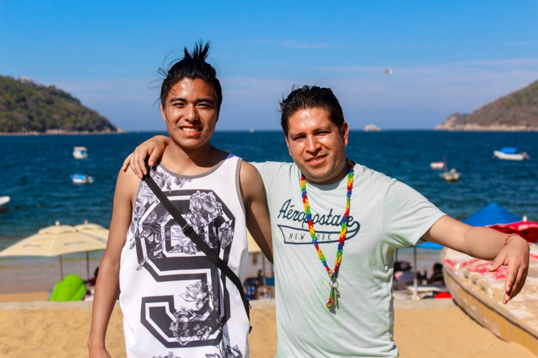Two people pose together on a beach.