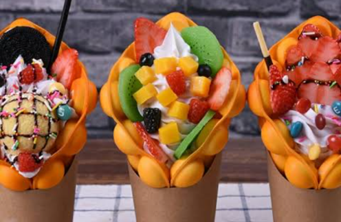 Catrina Acx. con una crepe de frutas en el plato y la vitrina de postres iluminada