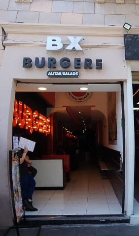 BX BURGERS counter displaying a burger with baguette bun and a side of Doritos