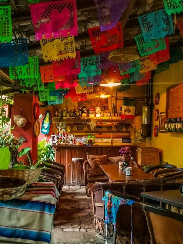 Casa Amacueca, Fonda del Pueblo — patio con mesas de madera, platos de cochinita pibil y chilaquiles bajo luz natural