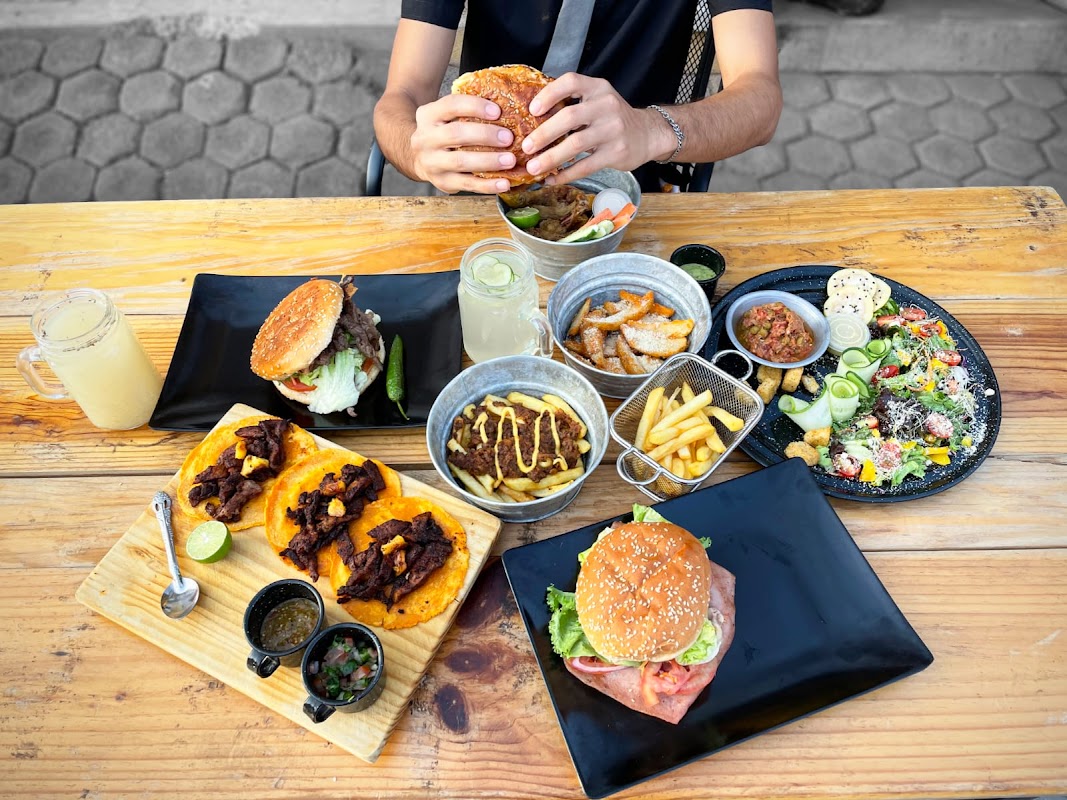 D'Anto Cocina Fusión con su hamburguesa de piña en primer plano, acompañada de papas fritas crujientes