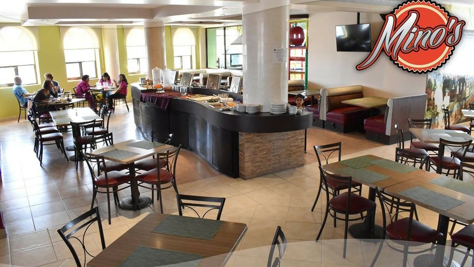 Área de buffet en Minos Restaurant Bar con platos de enchiladas, guisada y barra de bebidas