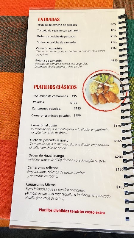 Interior del restaurante Mariscos El Yuyo con una tabla de camarones al ajillo y una cerveza fría