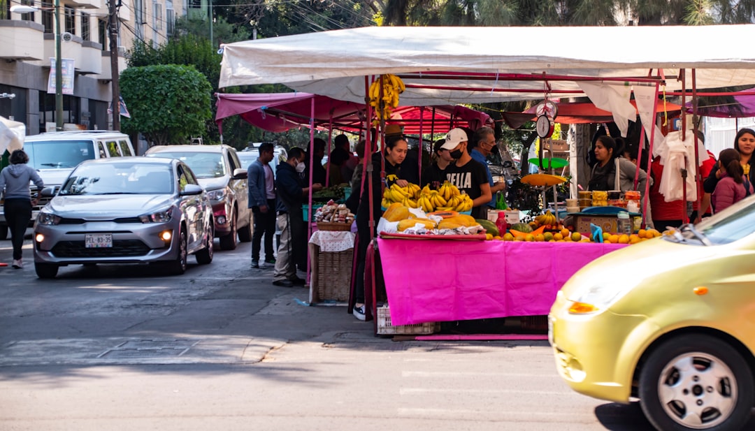 a yellow car is parked in front of a fruit stand