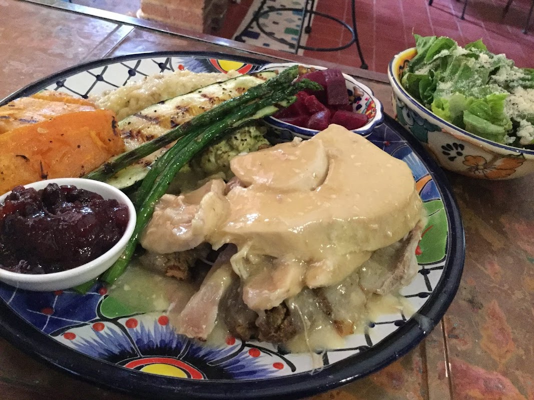 Jardín iluminado de Sandrina’s con platos de pollo souvlaki y tarta de lima sobre la mesa