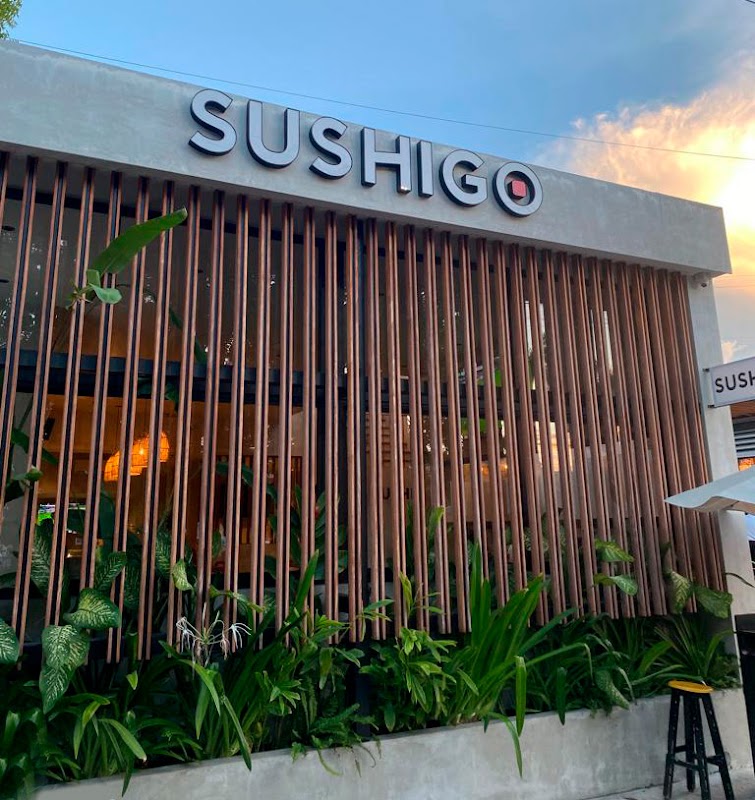 Sushi Central NID Puerto Cancún – fachada con letrero iluminado y una bandeja de sushi variado sobre una mesa al aire libre