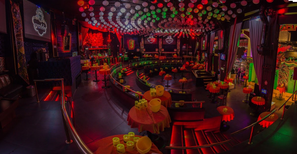 Pista de baile iluminada en Mandala Nightclub, con luces de neón y DJ en acción