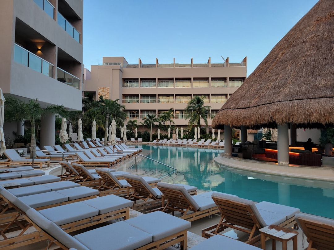 A hotel pool with lounge chairs and a thatched roof