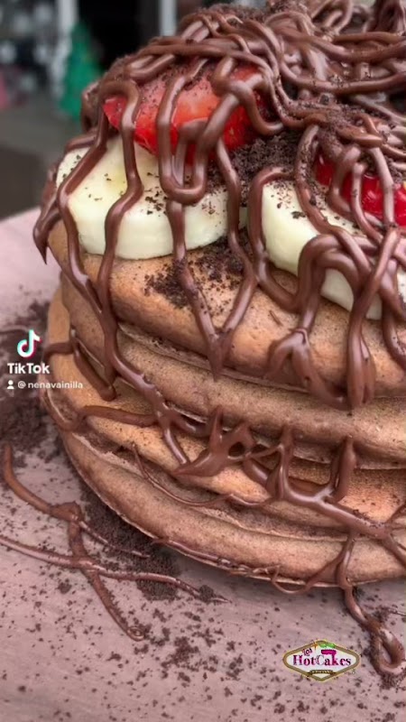 Una pila de hotcakes con frutas y jarabe en la mesa de Los HotCakes de Nena Vainilla — detalle del plato