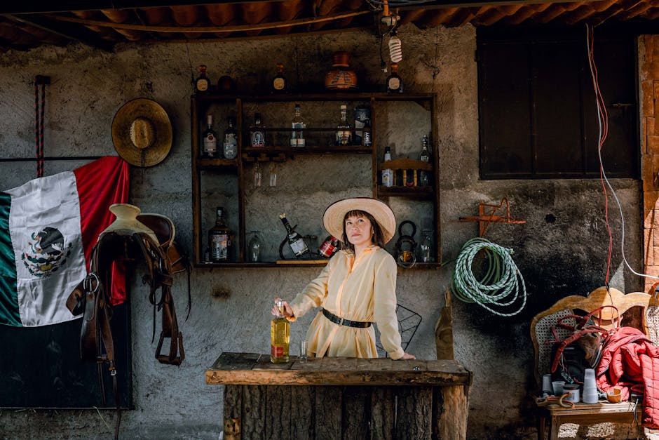 A woman in a cowboy hat serves whiskey in a rustic Mexican bar setting.