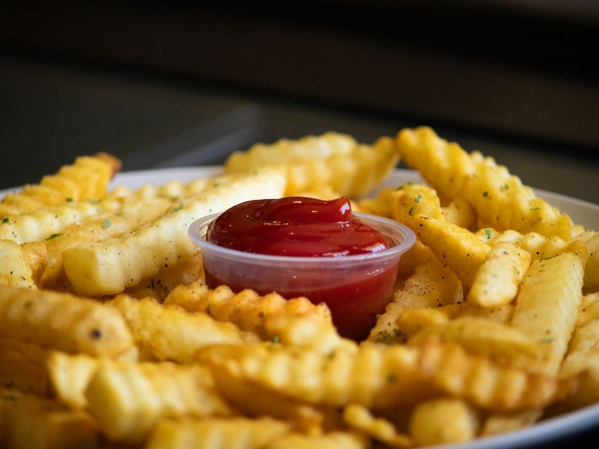 A plate of crispy crinkle-cut French fries with a side of ketchup, perfect for food enthusiasts.