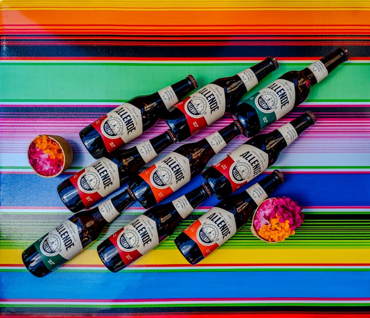 A vibrant display of Allende beer bottles on a colorful Mexican textile with flower petals.