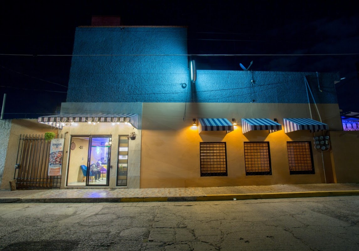 Buffa Wings con alitas crujientes y micheladas en la barra — interior con luces neón y ambiente de música alta