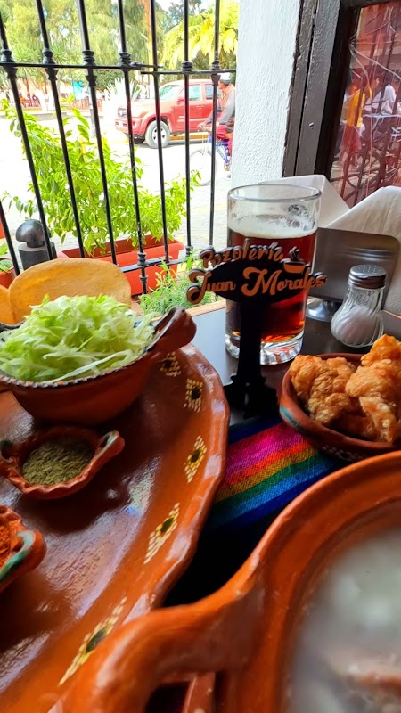 Exterior de Pozoleria Juan Morales con su letrero rojo y una olla de pozole humeante en primer plano
