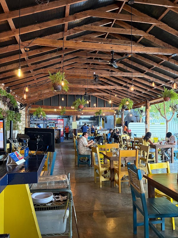 Interior de Artesano Fondita Huasteca, con mesas de madera y una cocina visible donde se preparan enchiladas