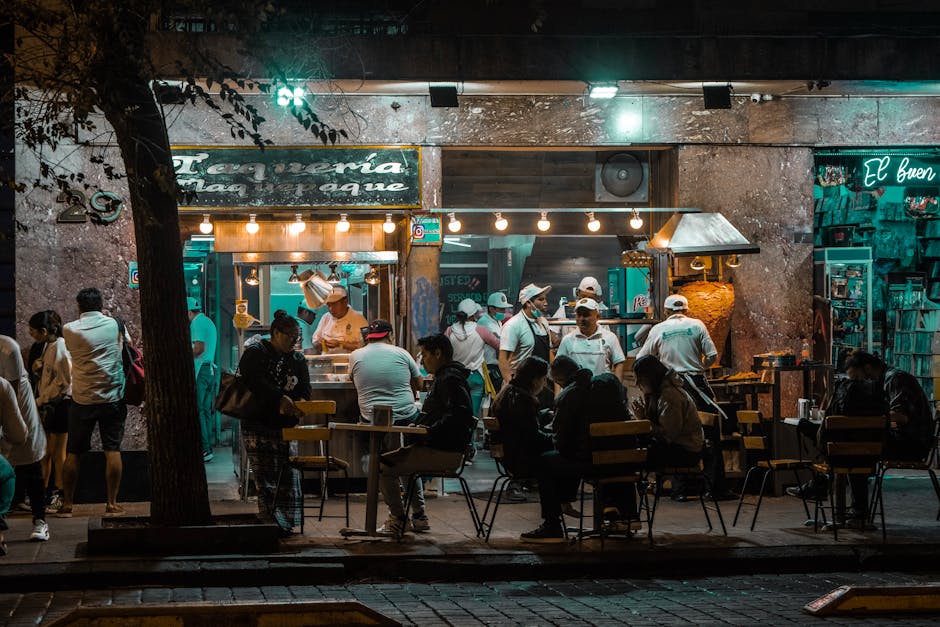Crowded urban street restaurant at night, capturing lively city nightlife and dining.
