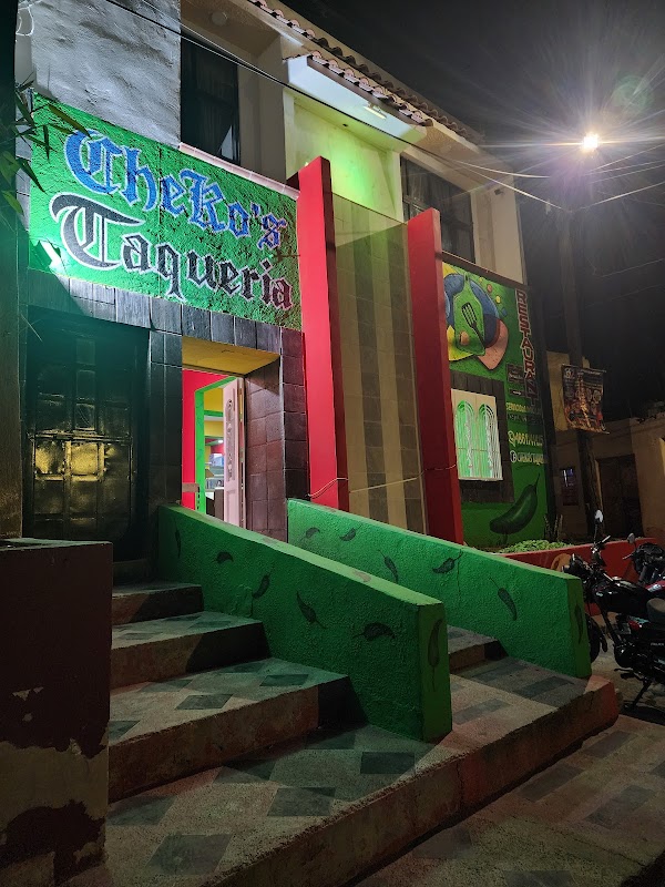 Fachada colorida de Cheko's Taquería en la esquina Pipila, con letrero iluminado y clientes en la acera