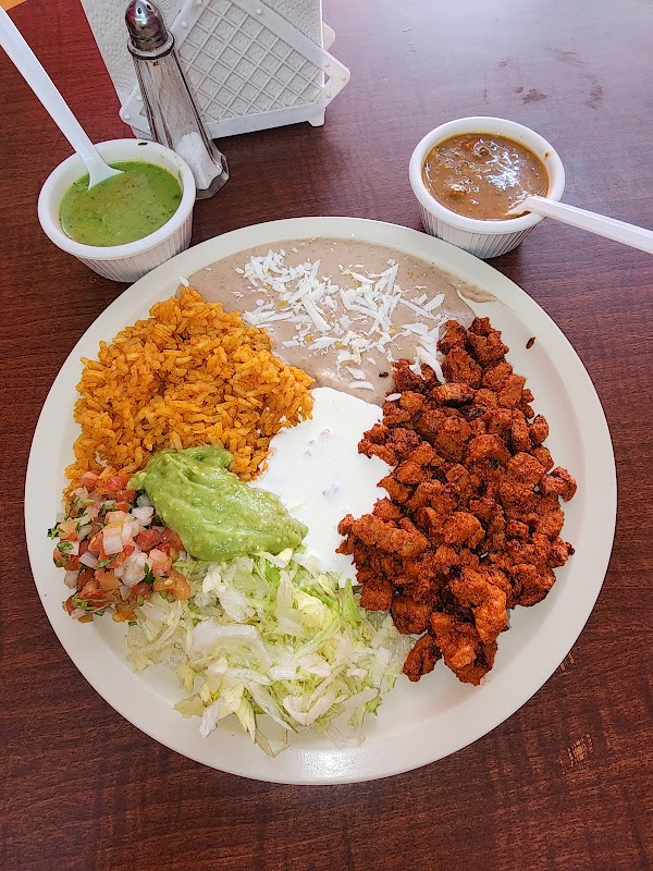 Plato de tacos al pastor en Cheko's Taquería, tortillas recién hechas, carne jugosa y piña, capturado en primer plano