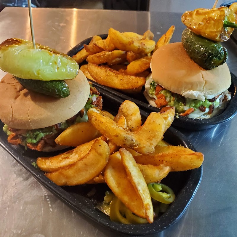 Bar de EL BUCANERO mostrando micheladas y arrachera en la parrilla, con luces bajas y ambiente animado