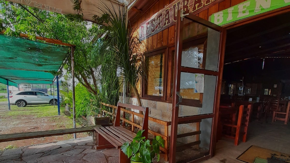 Exterior colorido de La cabaña de Blas con mesas al aire libre y una botella de mezcal sobre la barra — captura el ambiente matutino