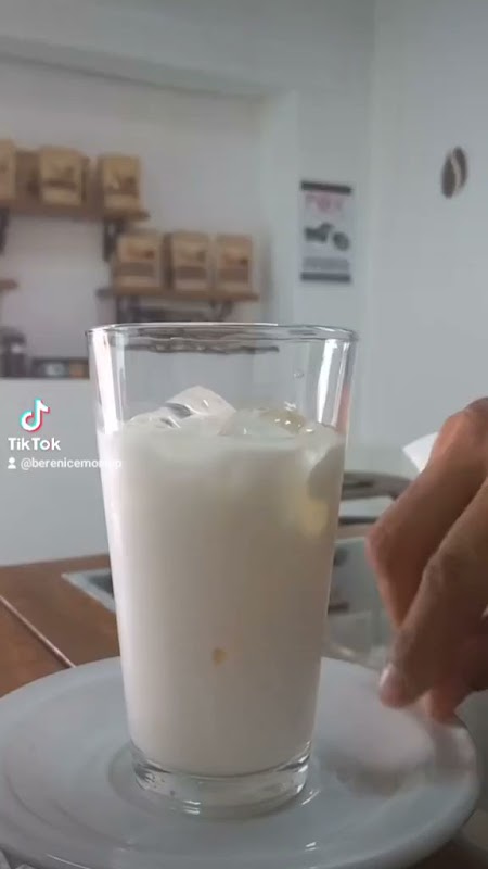 Cappuccino con espuma y miel en UN CAFÉ DE ALTURA, taza sobre la barra de madera — detalle de la bebida