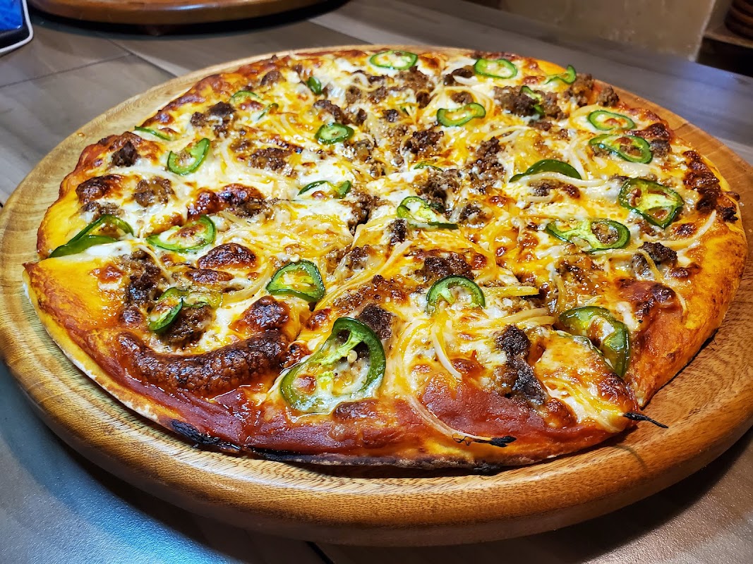 Pizza hawaiana recién salida del horno de ladrillo en Casa Grande Pizza Restaurante, con queso fundido y piña brillante