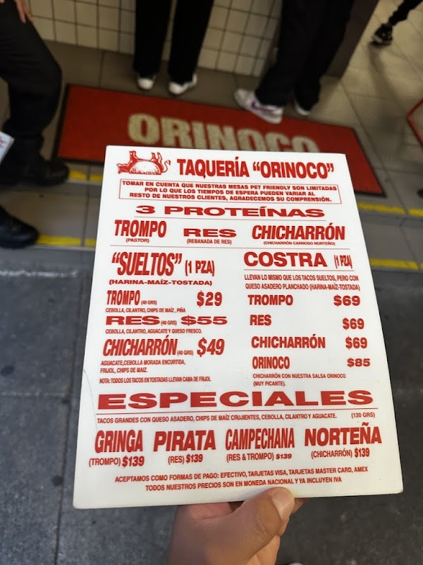 Interior de Taquería Orinoco, barra de tacos, mesas de madera y camareros sirviendo a la multitud