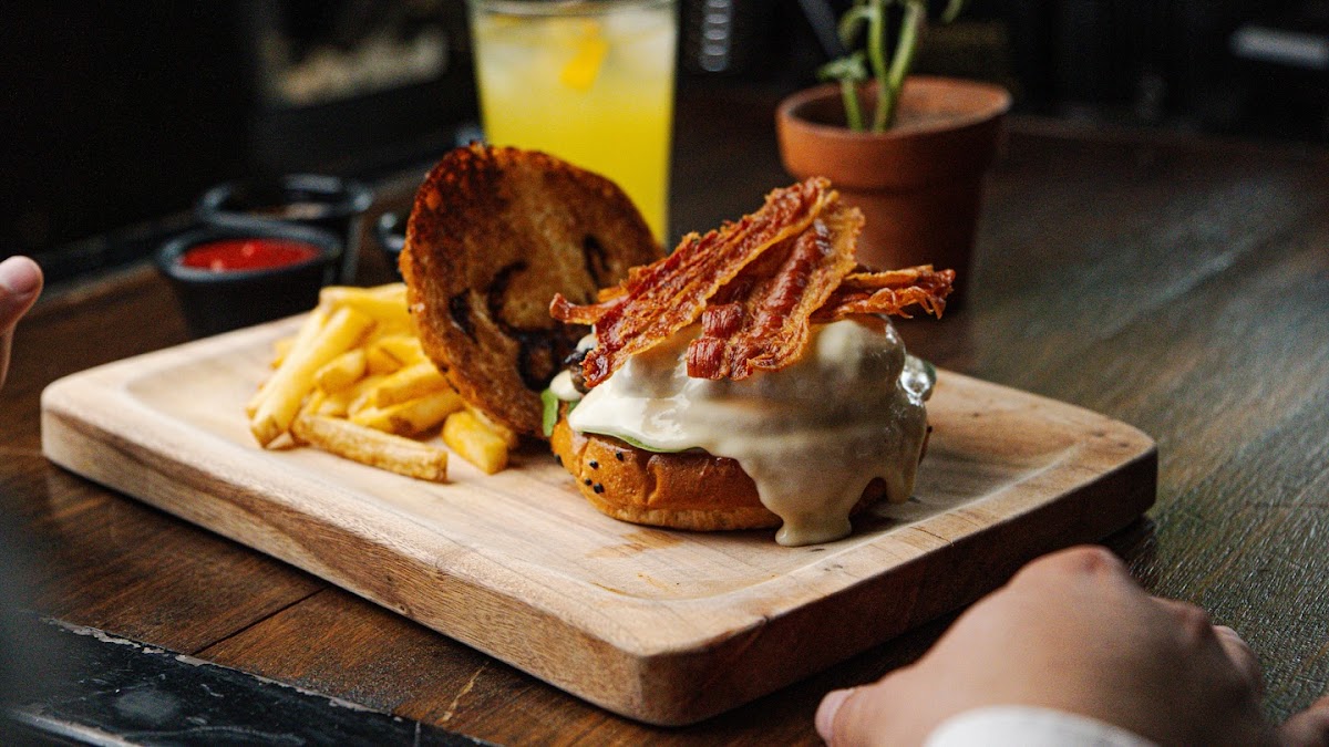 Primer plano de la hamburguesa de ribeye con salsa de habanero, pan brioche y papas trufadas en el plato — detalle gastronómico