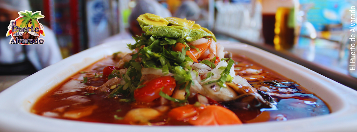 Plato de aguachile de camarón en bandeja azul, mostrando camarones, chile verde y rodajas de pepino