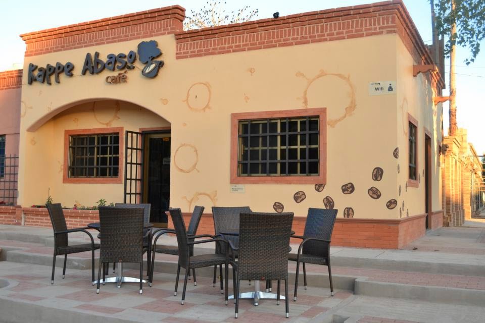 Kappe Abaso Café con una taza de espresso de menta y un mollete abierto, interior con mesas de madera