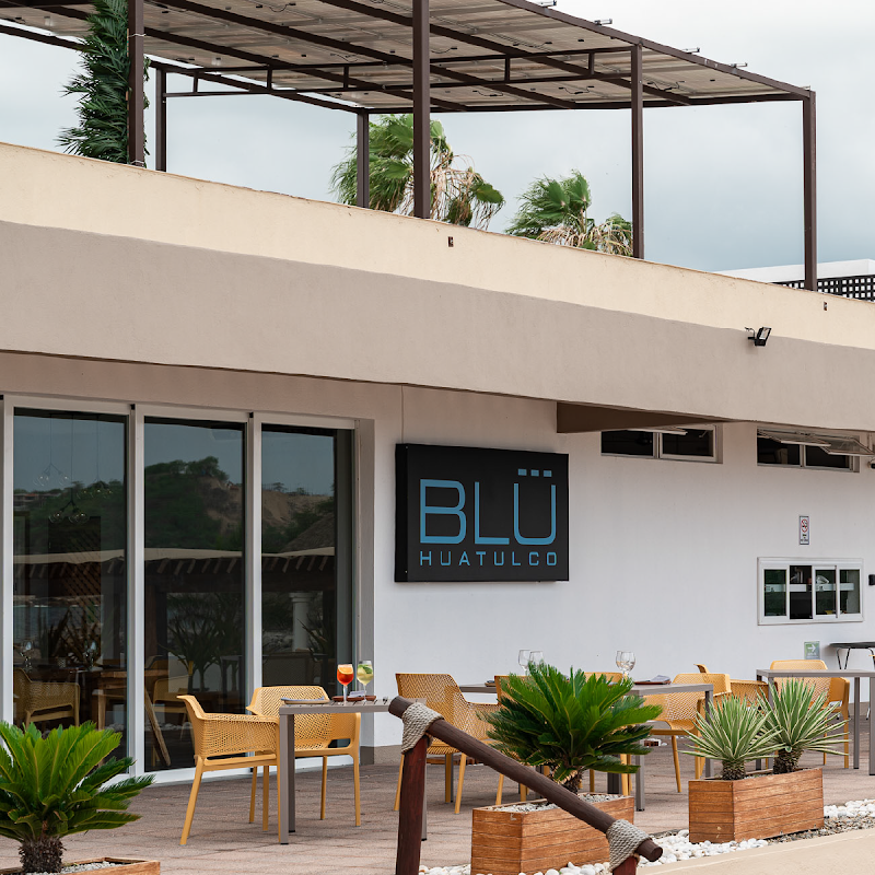 Cóctel de mezcal en la barra de Blu Huatulco, con luces tenues y vista al mar de fondo