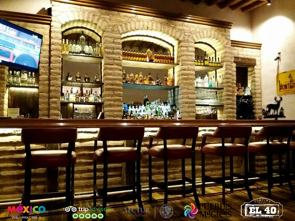 Cantina El 40 exterior con su colorido letrero y un bartender sirviendo un mezcal en vaso tradicional