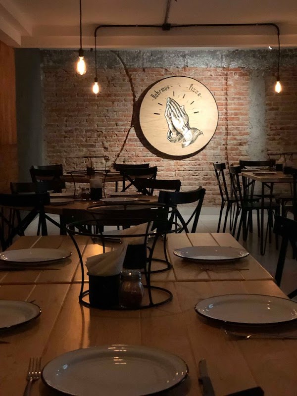 Interior del local mostrando la barra de madera, el pizzaiolo trabajando la masa y la decoración con música de los 80