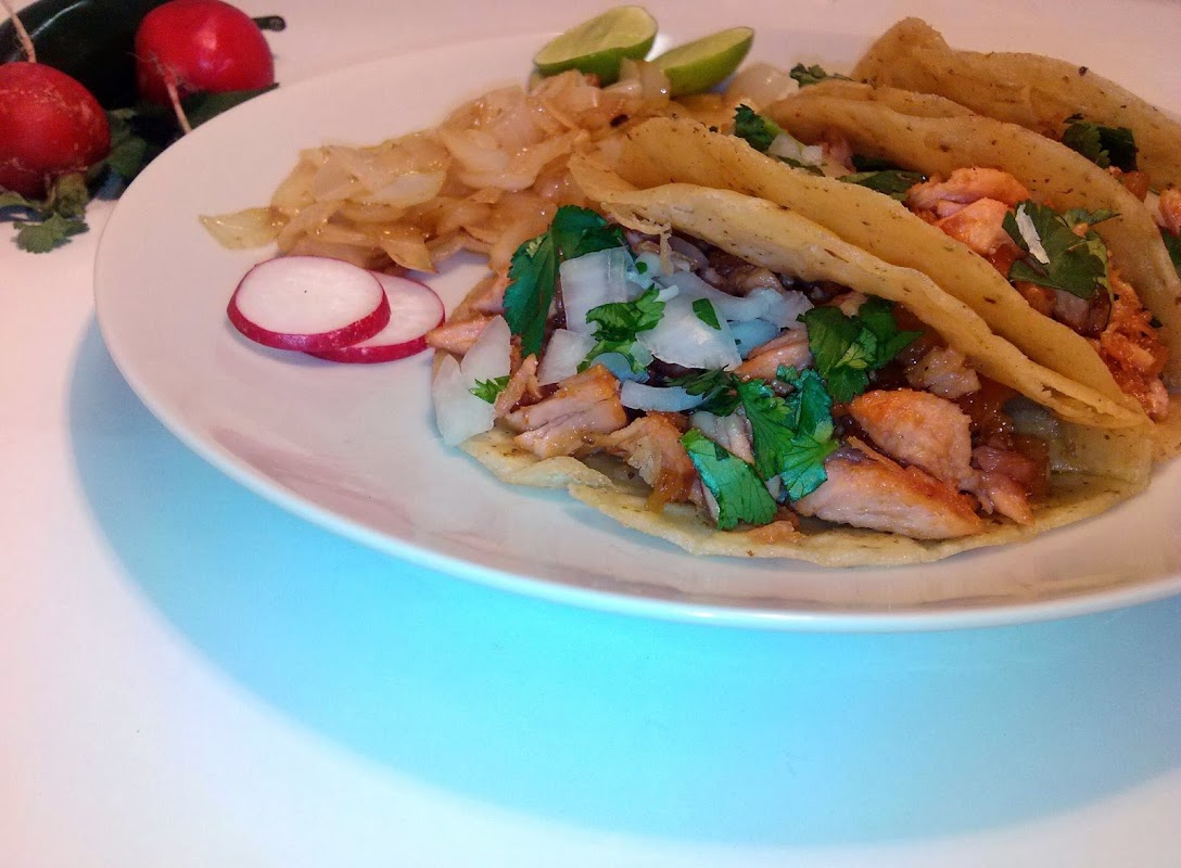 Ke Takazo mostrando su cocina abierta y una bandeja de cochinita pibil al atardecer