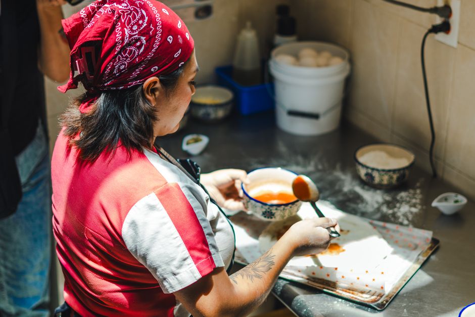 A woman prepares Mexican food in a kitchen, highlighting traditional culinary practices.