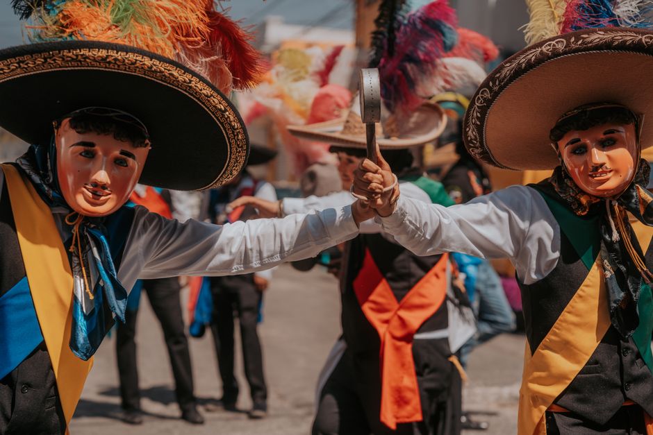 Vibrant celebration with masked dancers in traditional attire at a Mexican festival in Puebla.